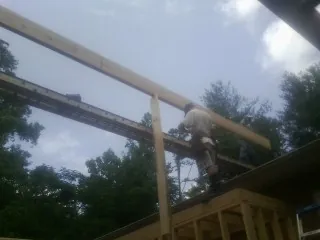 Carpenter setting a ridge beam over a new addition frame — Ice Dam Removal by Roofing Brothers in Burlington